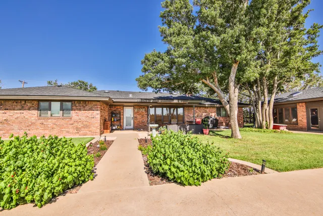 a front view of a house with a garden and trees