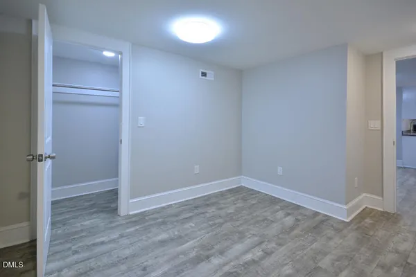 a view of an empty room with closet and a window