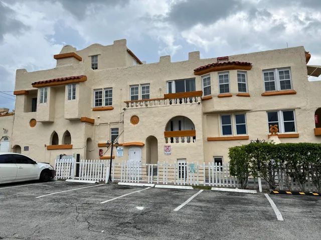 a view of a white house with large windows and fence