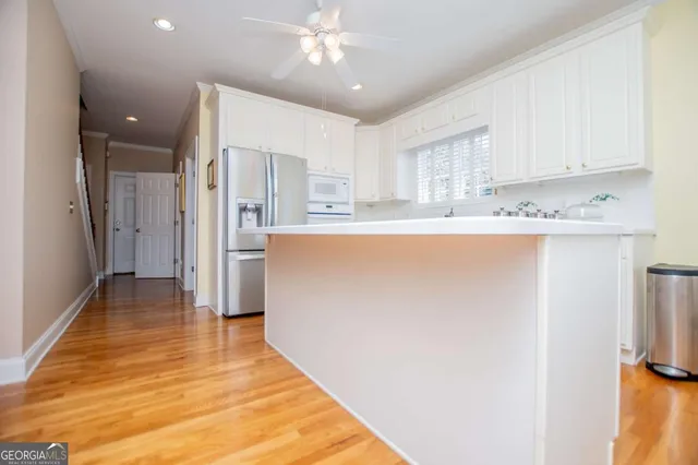 a view of a kitchen with kitchen island a sink wooden floor and a refrigerator