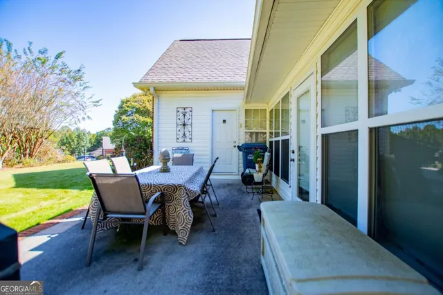 a view of a patio with table and chairs and potted plants with wooden floor and fence