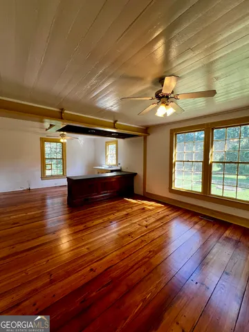 a view of empty room with wooden floor and fan