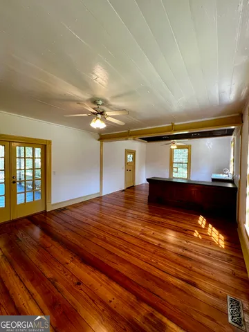 a view of an empty room with window and wooden floor