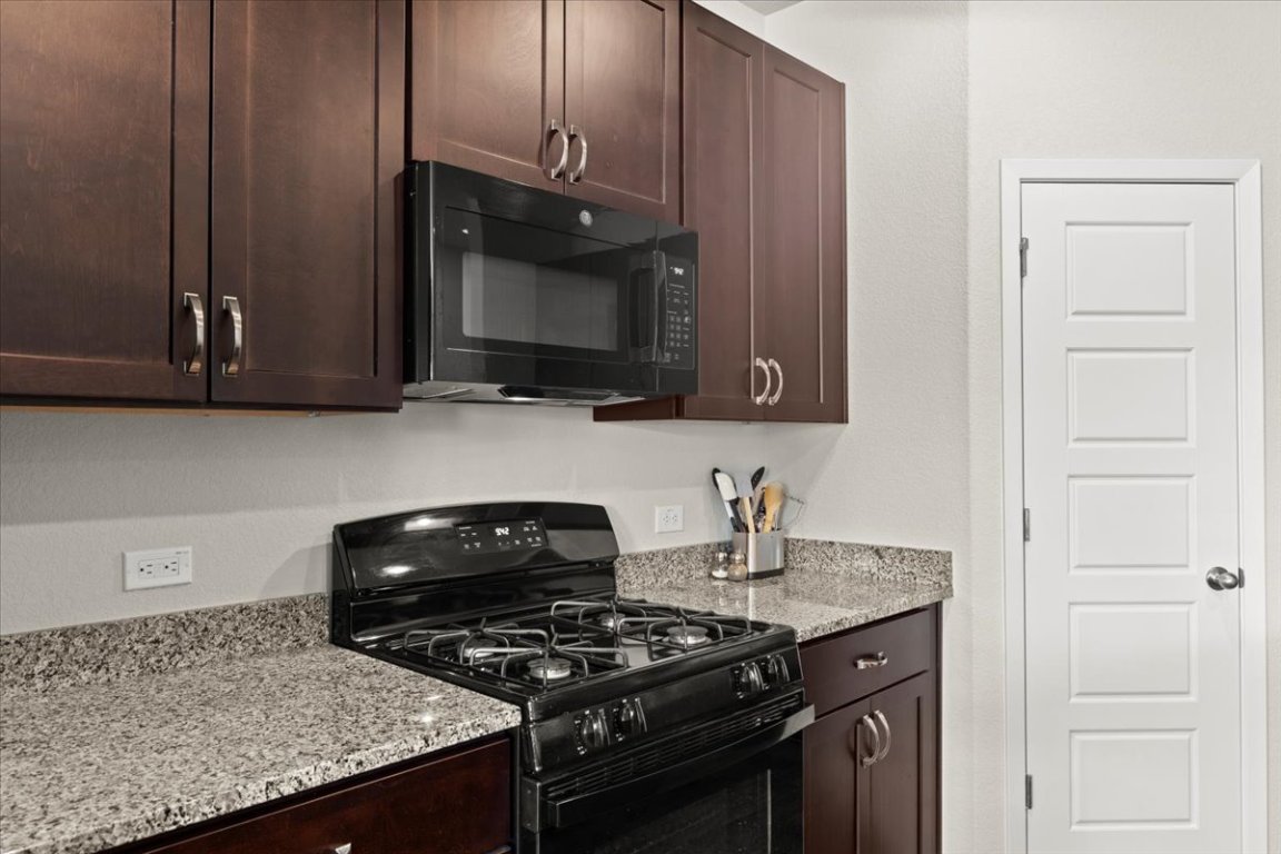1296 Teychas Drive Kyle, TX 78640 - Photo 11 of 39 a kitchen with granite countertop a stove and a microwave