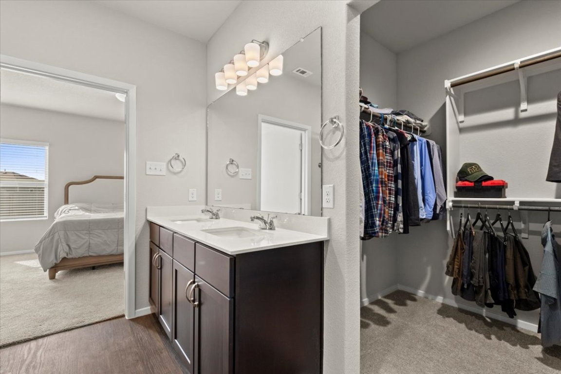1296 Teychas Drive Kyle, TX 78640 - Photo 18 of 39 Bathroom featuring double vanity, ensuite bath, baseboards, and a spacious closet