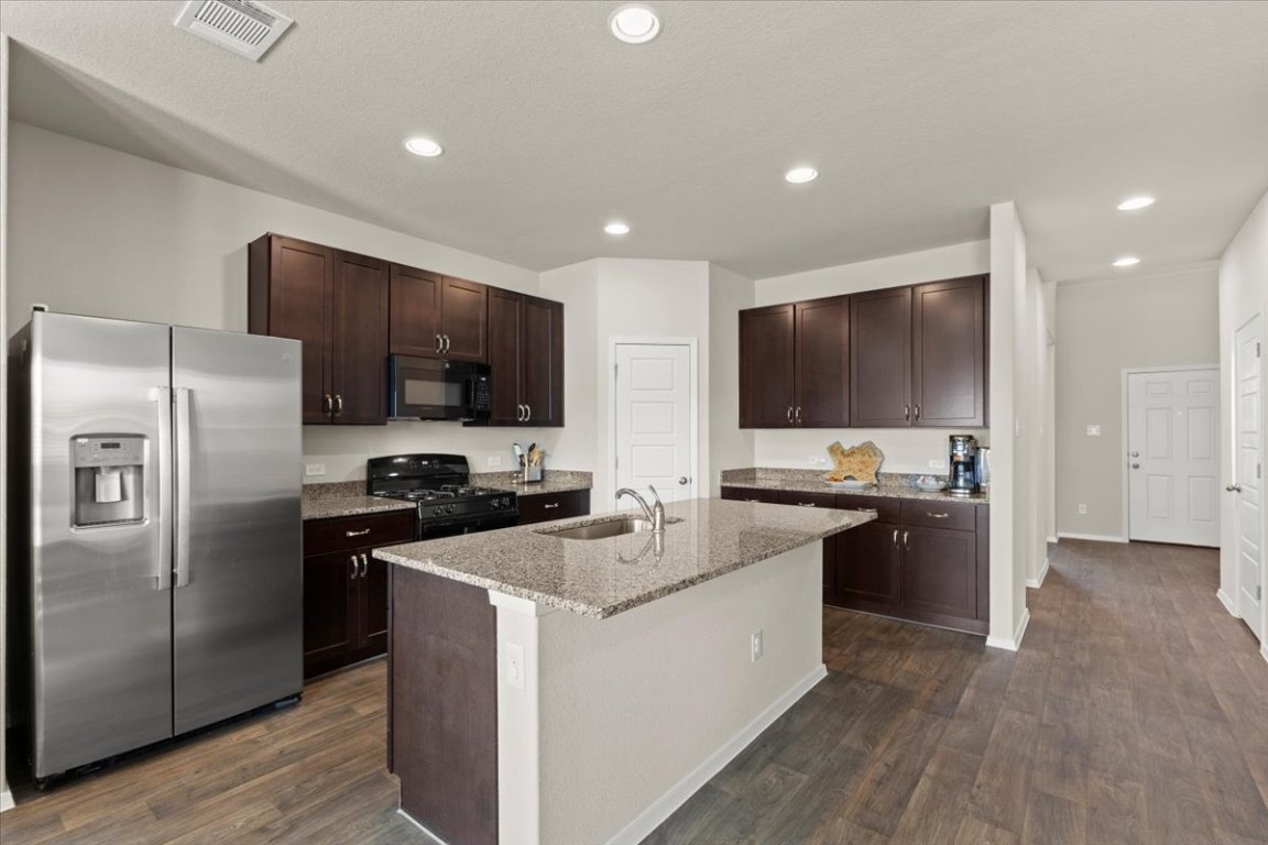1296 Teychas Drive Kyle, TX 78640 - Photo 3 of 39 a kitchen with stainless steel appliances granite countertop a stove top oven a refrigerator and a sink
