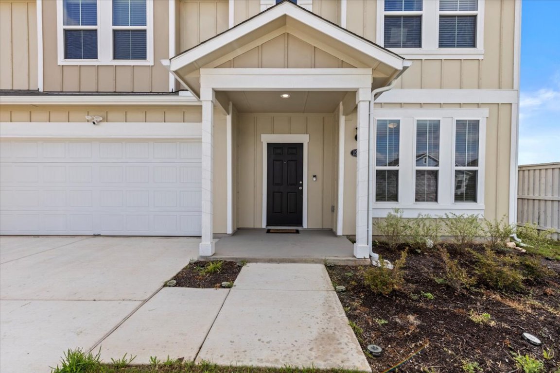 1296 Teychas Drive Kyle, TX 78640 - Photo 38 of 39 View of exterior entry with board and batten siding, driveway, and a garage