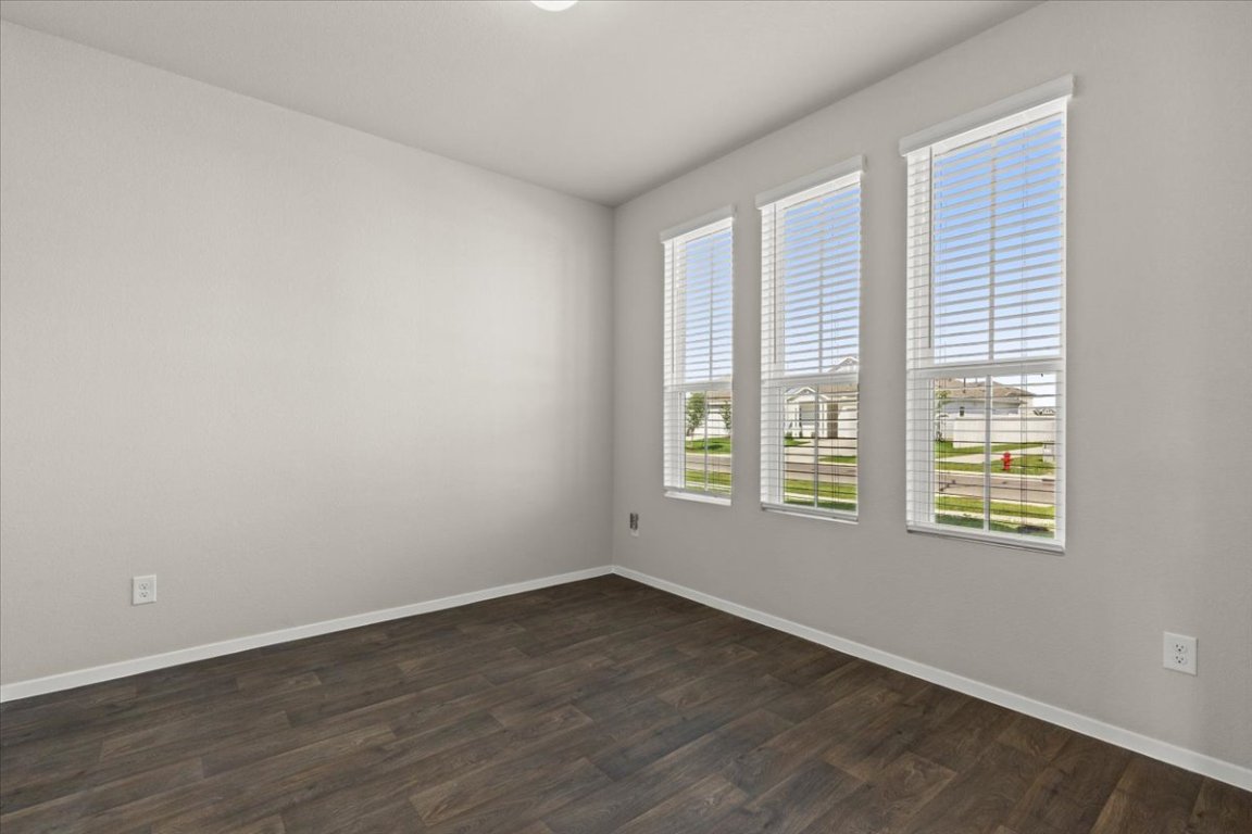 1296 Teychas Drive Kyle, TX 78640 - Photo 5 of 39 an empty room with wooden floor and windows