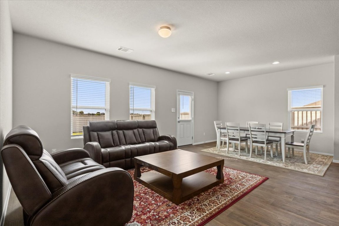 1296 Teychas Drive Kyle, TX 78640 - Photo 8 of 39 a living room with furniture a rug and a dining table with wooden floor