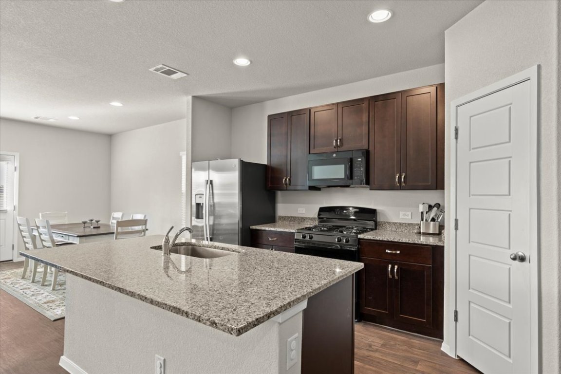 1296 Teychas Drive Kyle, TX 78640 - Photo 10 of 39 a kitchen with kitchen island granite countertop a sink stove and refrigerator