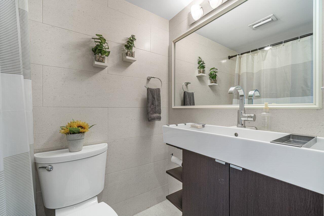 2311 Northeast 36th Street, Unit 1A Lighthouse Point, FL 33064 - Photo 18 of 29 a bathroom with a sink a mirror and a toilet