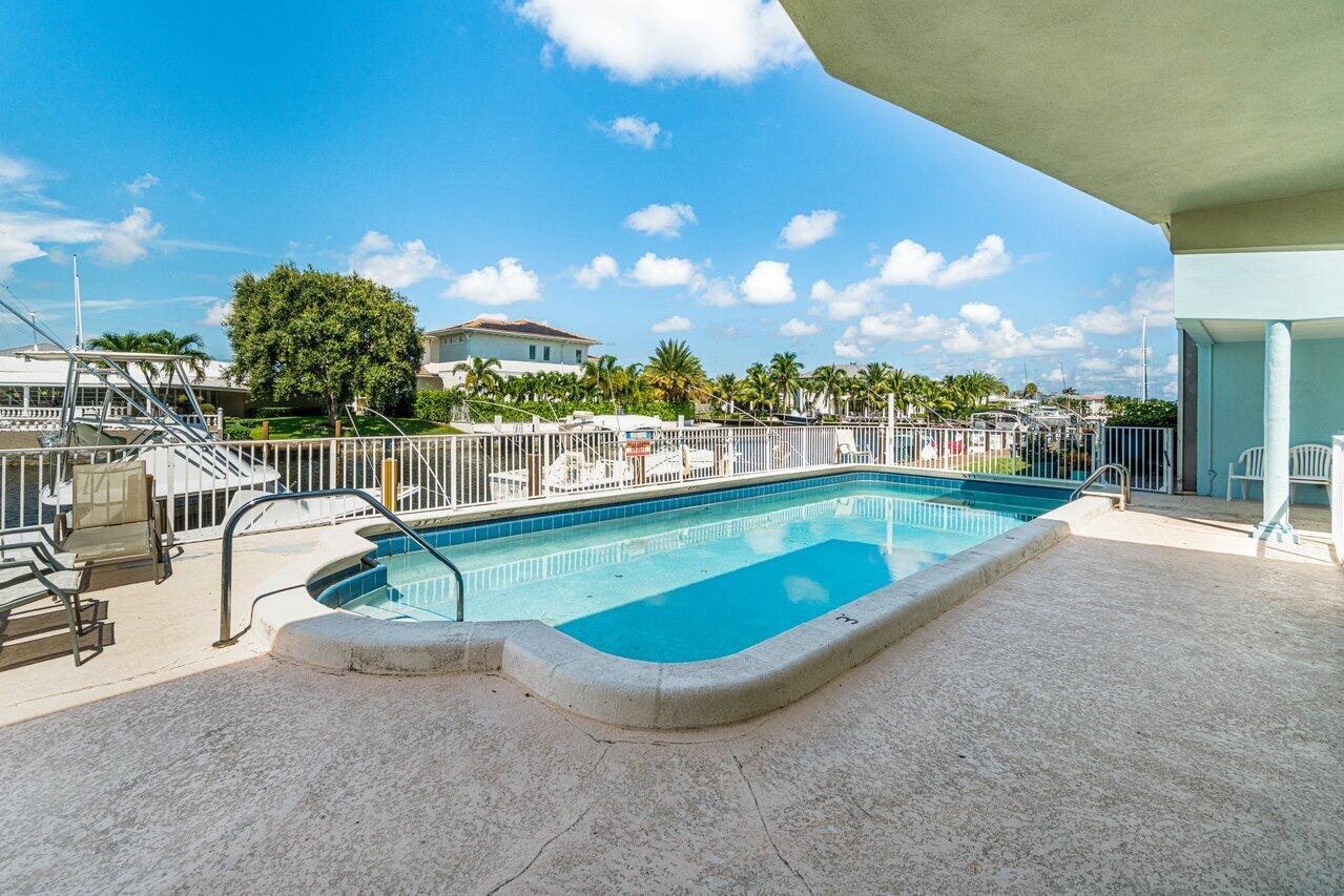2311 Northeast 36th Street, Unit 1A Lighthouse Point, FL 33064 - Photo 29 of 29 a view of a swimming pool with a lounge chair and a large tree