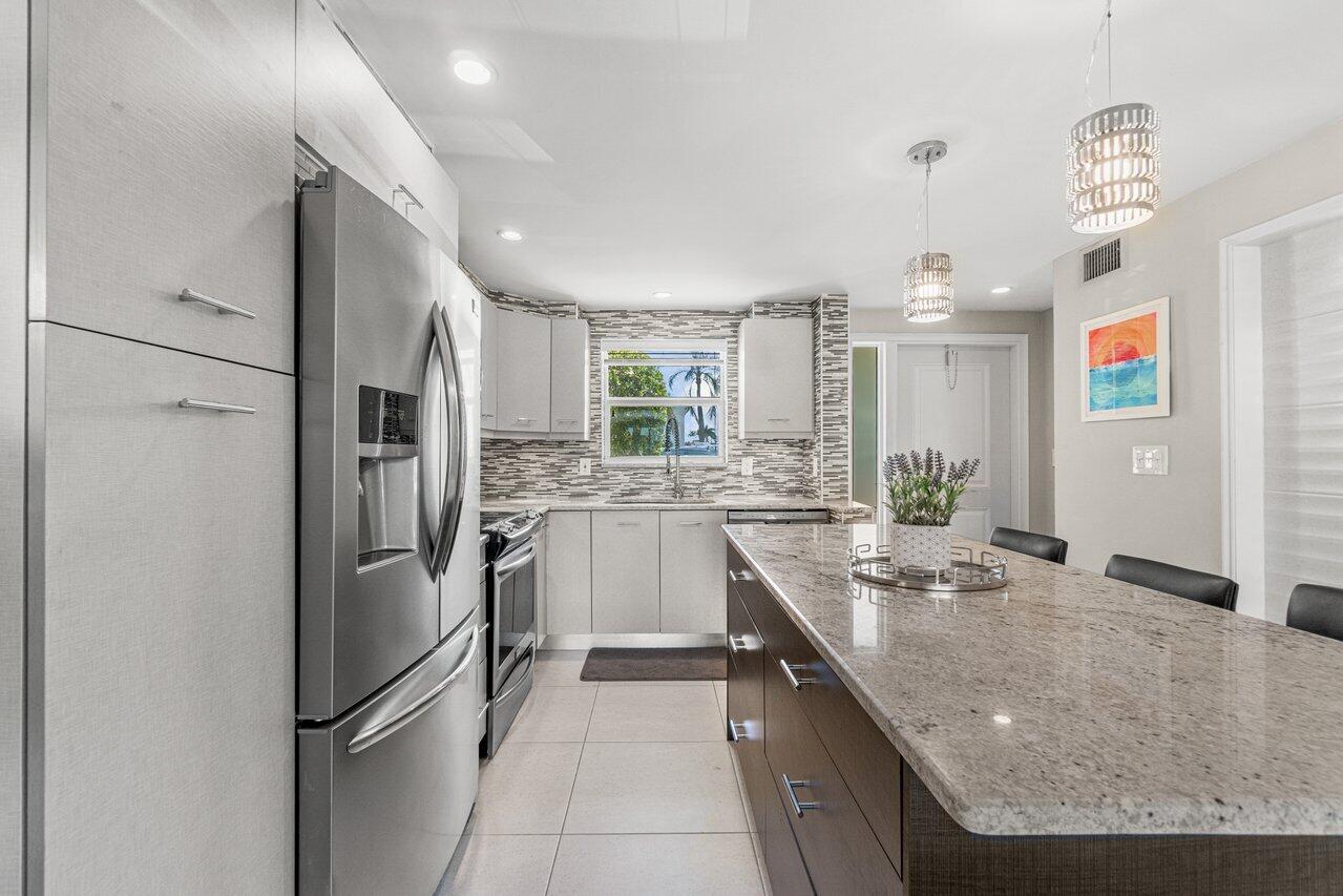 2311 Northeast 36th Street, Unit 1A Lighthouse Point, FL 33064 - Photo 3 of 29 a kitchen with stainless steel appliances granite countertop a sink refrigerator and microwave