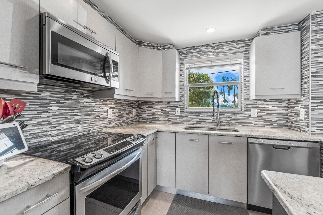 2311 Northeast 36th Street, Unit 1A Lighthouse Point, FL 33064 - Photo 4 of 29 a kitchen with stainless steel appliances granite countertop a stove microwave and sink