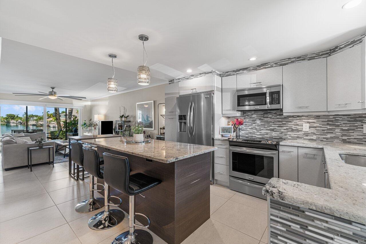 2311 Northeast 36th Street, Unit 1A Lighthouse Point, FL 33064 - Photo 5 of 29 a kitchen with kitchen island stainless steel appliances a sink stove and microwave