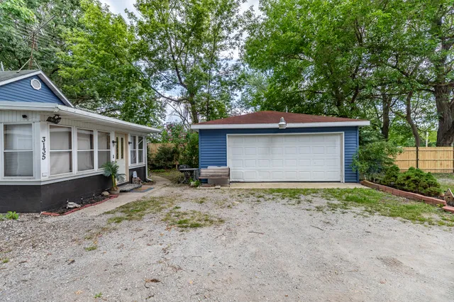 a view of a house with a yard plants and large tree