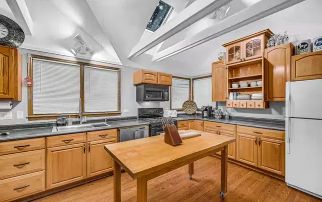 a kitchen with stainless steel appliances granite countertop a stove a sink dishwasher and cabinets with wooden floor