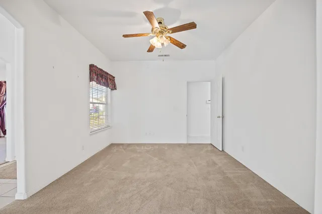 an empty room with a window and a ceiling fan