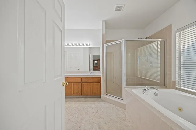 a bathroom with a bathtub a double vanity sink and mirror