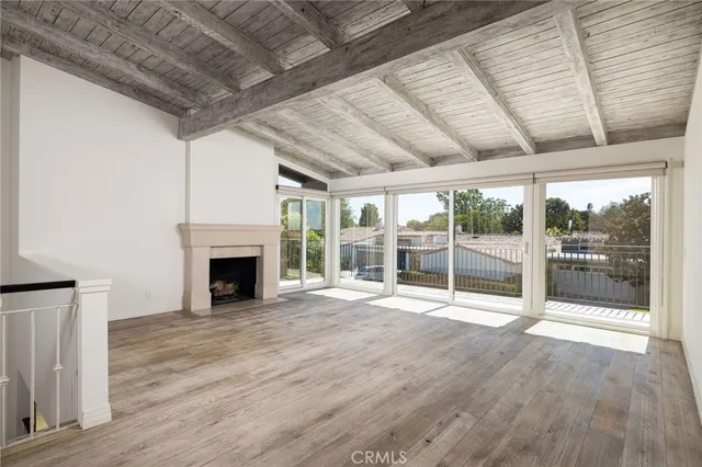 a view of an empty room with wooden floor and fireplace