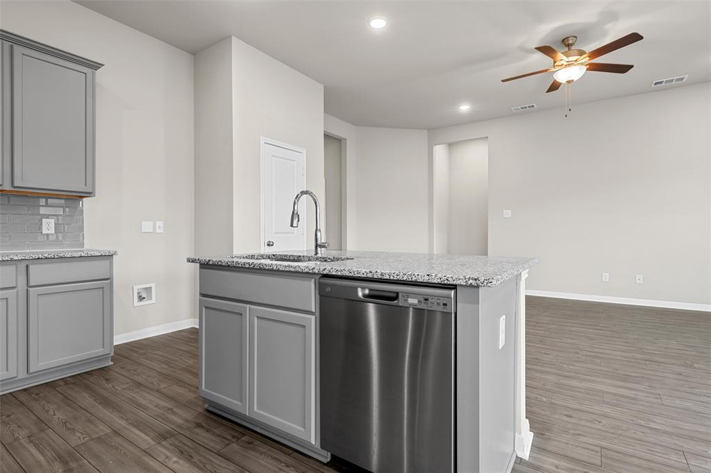 3208 Dottavio Road Lorena, TX 76655 - Photo 8 of 31 Kitchen island featuring a stainless steel dishwasher, an integrated sink with a gooseneck faucet, and a speckled countertop