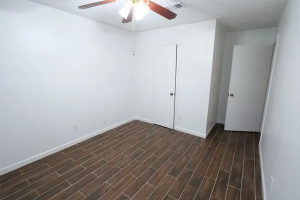 an empty room with wooden floor fan and windows