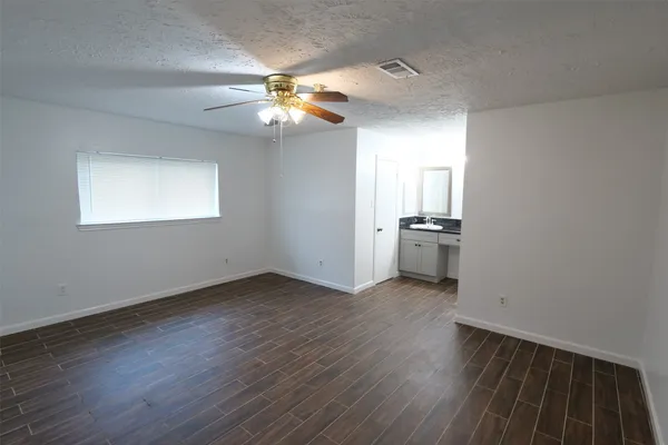 an empty room with wooden floor chandelier fan and windows