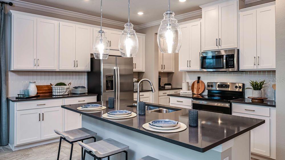 6917 Prairie Oak Way Nokomis, FL 34275 - Photo 4 of 28 a kitchen with stainless steel appliances granite countertop a stove a sink a refrigerator and white cabinets