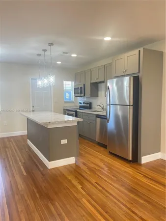 a large kitchen with stainless steel appliances granite countertop a refrigerator a sink dishwasher a stove with wooden floors