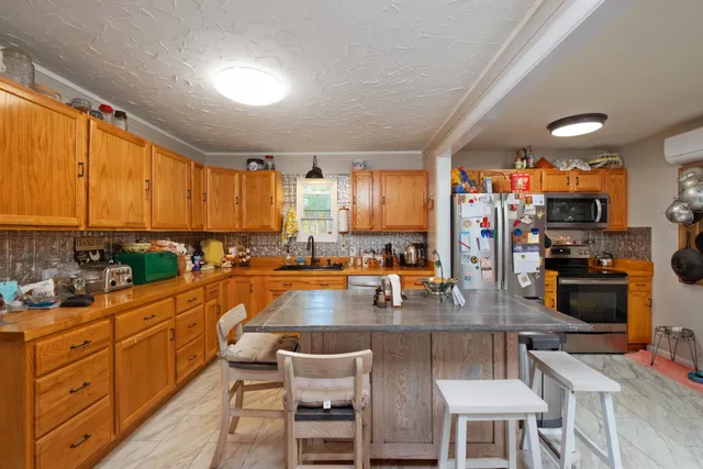 a room with stainless steel appliances kitchen island granite countertop a stove and a view of living room