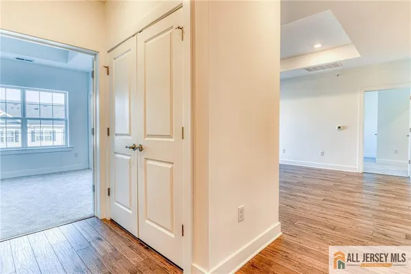 a view of a hallway with wooden floor and closet