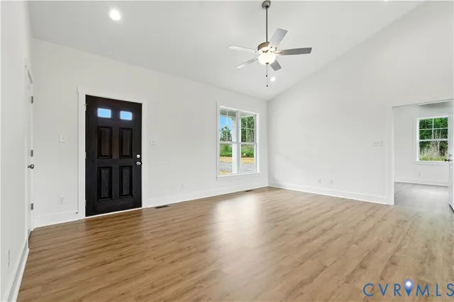 an empty room with wooden floor chandelier and windows