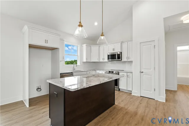 a kitchen with stainless steel appliances granite countertop a sink a stove and a wooden floors