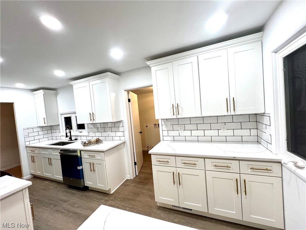 7687 Ragall Parkway Cleveland, OH 44130 - Photo 8 of 37 Kitchen with white cabinetry, dark hardwood / wood-style flooring, dishwasher, and tasteful backsplash
