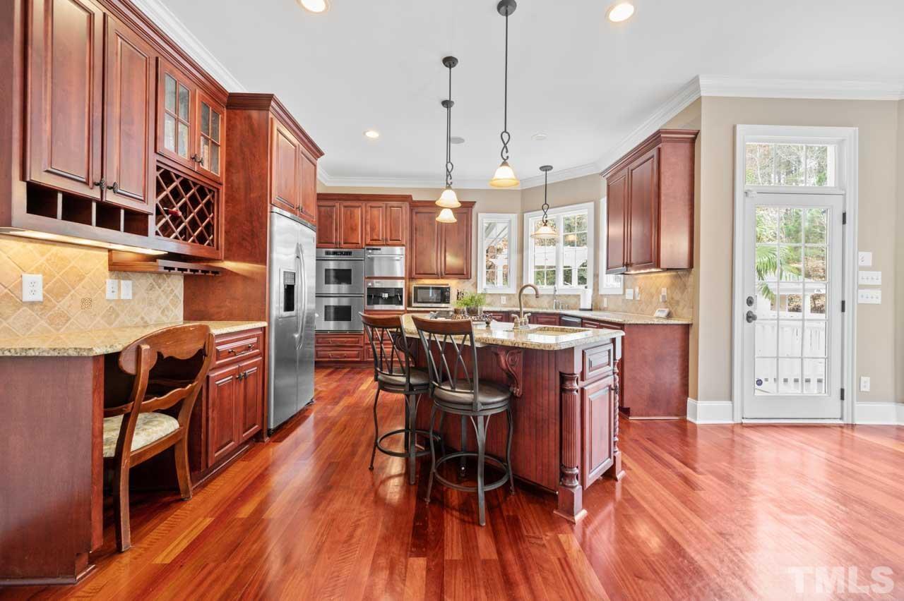 1605 Sharnbrook Court Raleigh, NC 27614 - Photo 24 of 63 a open kitchen with stainless steel appliances granite countertop a stove a refrigerator a oven a sink a dining table and chairs with wooden floor