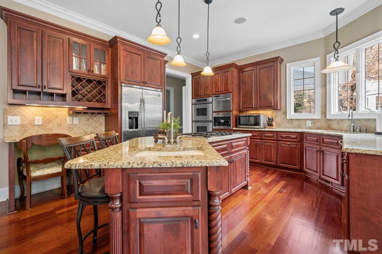 1605 Sharnbrook Court Raleigh, NC 27614 - Photo 27 of 63 a kitchen with kitchen island granite countertop wooden floors wooden cabinets a center island and appliances