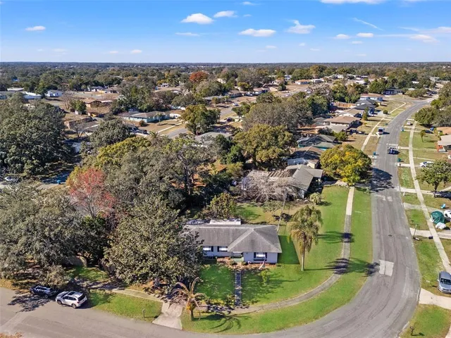 an aerial view of residential houses with outdoor space and trees