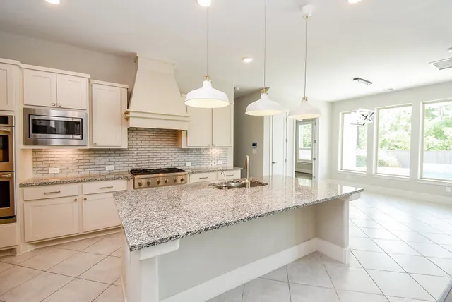 an empty room with wooden floor fireplace and windows