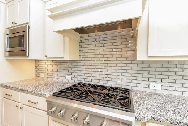 a kitchen with stainless steel appliances granite countertop a stove a sink and a microwave
