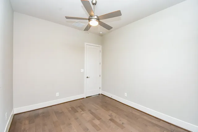 an empty room with ceiling fan and window