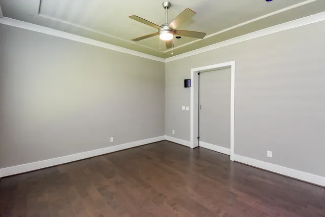 an empty room with a ceiling fan and wooden floor