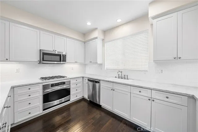 a kitchen with white cabinets stainless steel appliances and sink