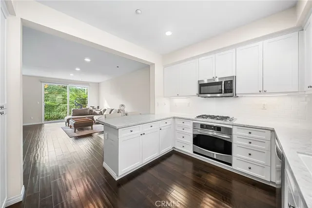 a kitchen with stainless steel appliances white cabinets a stove a sink and a microwave