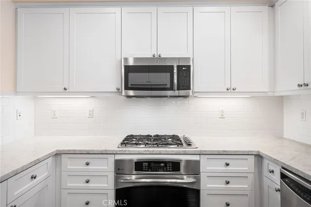 a kitchen with granite countertop white cabinets and stainless steel appliances