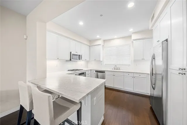 a kitchen with a sink a stove a refrigerator and white cabinets with wooden floor