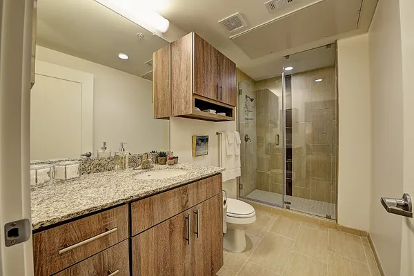 a bathroom with a granite countertop sink a toilet and shower