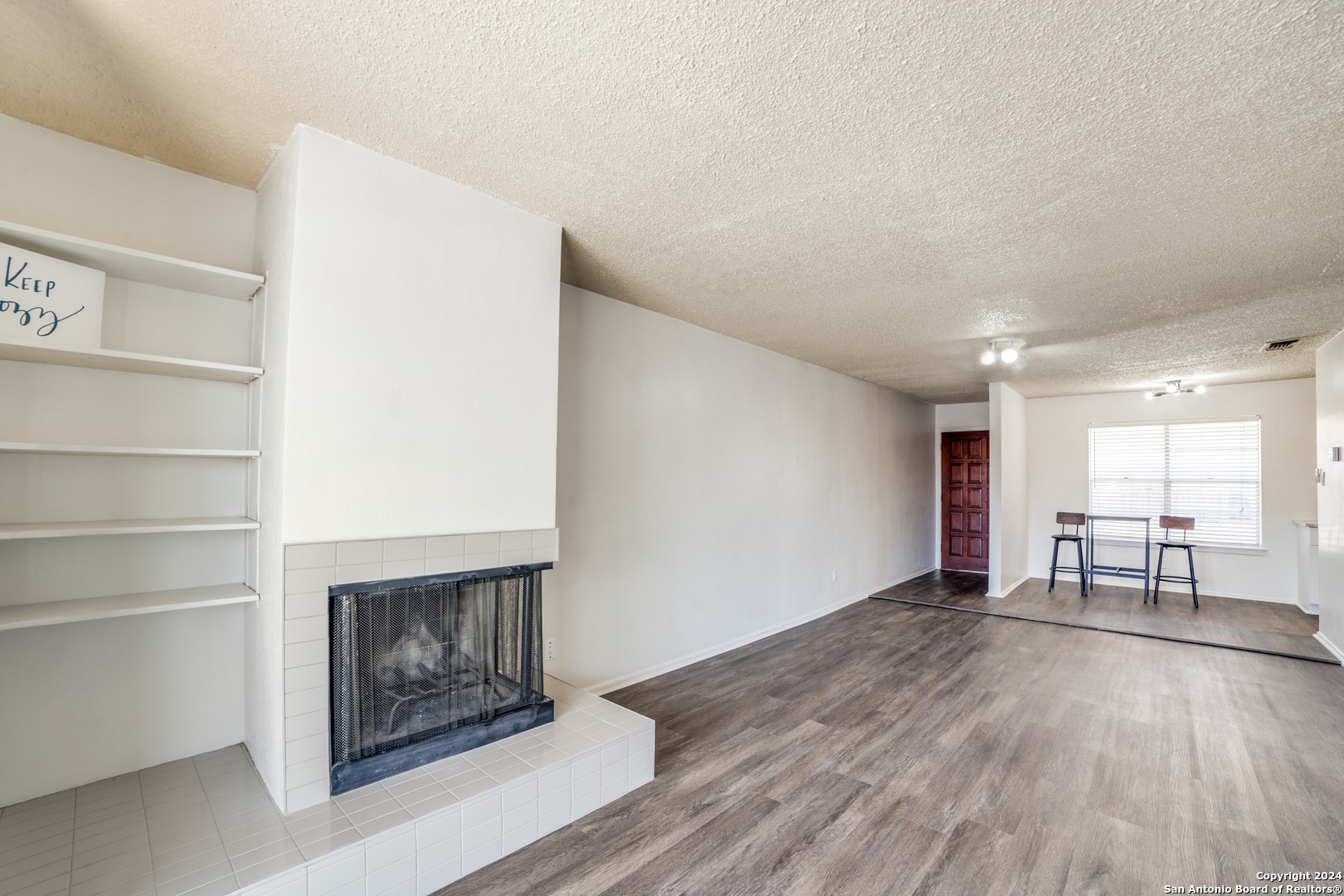 a view of empty room with a fireplace and wooden floor