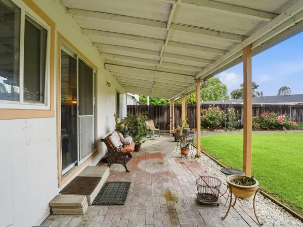 a view of a patio with table and chairs potted plants with wooden floor and fence