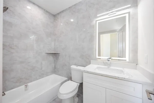a bathroom with a granite countertop toilet a sink and a bathtub