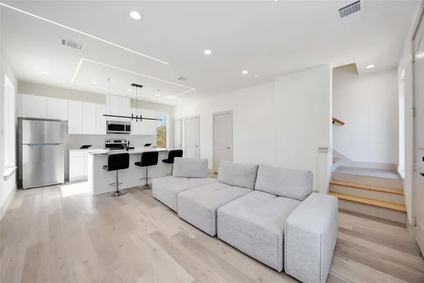 a living room kitchen with stainless steel appliances kitchen island granite countertop a refrigerator and a stove top oven